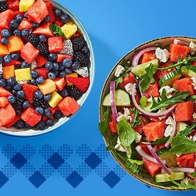 Top view of two vibrant summer salads in bowls on a blue background — one with mixed berries, dragon fruit, and mint, and the other with watermelon, cucumber, red onion, arugula, feta, and mint — healthy, colorful, and refreshing meal ideas.