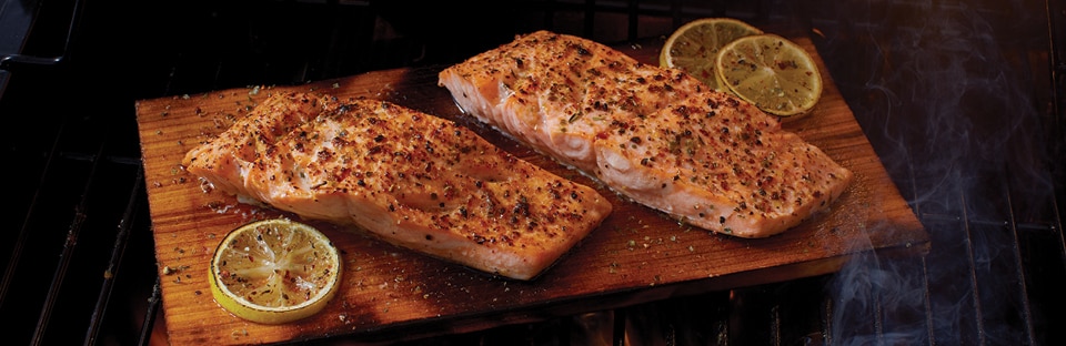 Salmon filets on wood plank on grill