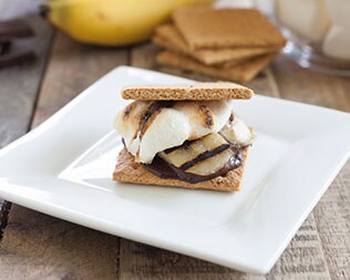 Smore with banana and drizzled chocolate on a white plate