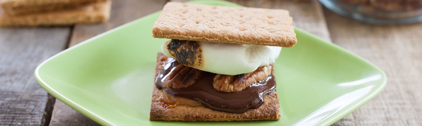 A smore with pecans and chocolate on a green plate