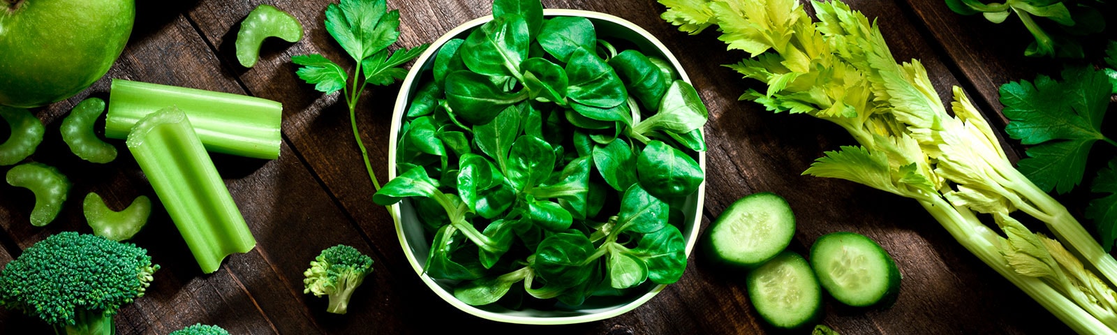 Green foods like spinach, celery, broccoli and cucumbers on a table
