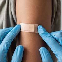 A clinician placing a bandage on a patient’s arm A clinician placing a bandage on a patient’s arm