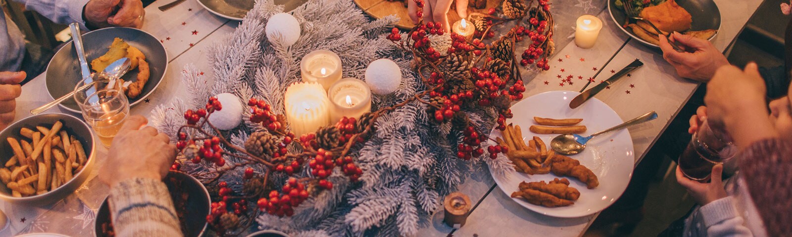 Fall decorated table with a candle centerpiece and people gathered around eating dinner