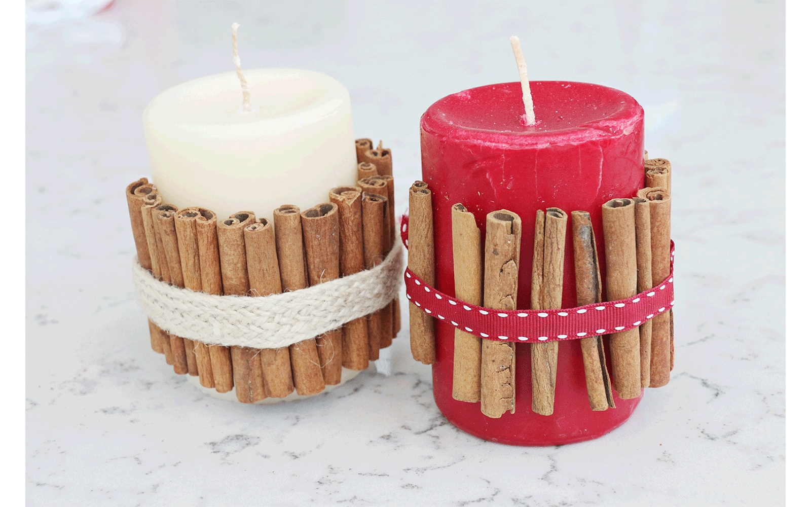 Red candle wrapped in cinnamon sticks held in place with ribbon sits inside of a white lantern with glass windows
