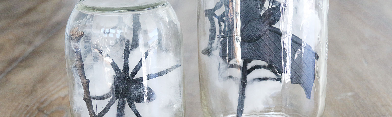 Mason jars with sticks, spiderwebs and a plastic spider or bat on the inside of each jar