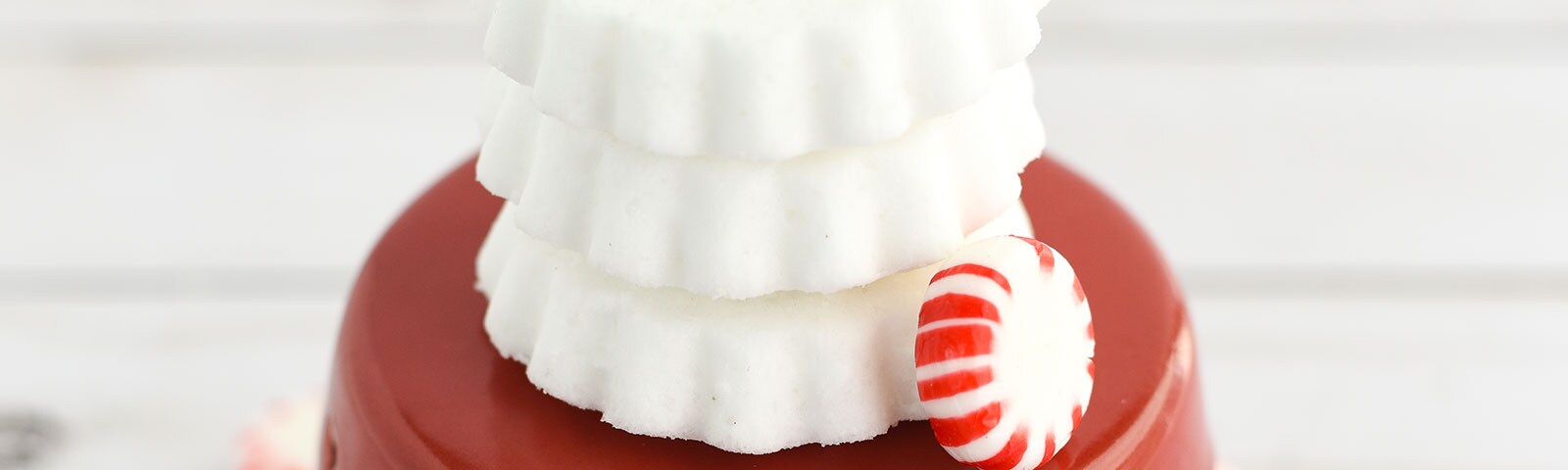 Stack of handmade bath bombs on a red stand with peppermint candies in the background