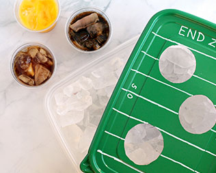 Finished tray: football-themed green rectangle container lid over ice that's ready to serve drinks
