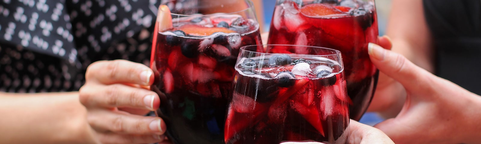 Individuals holding a glass of wine with ice cubes in it