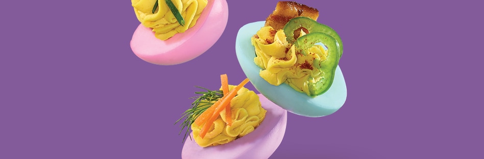 Assorted pastel deviled eggs with a variety of different toppings