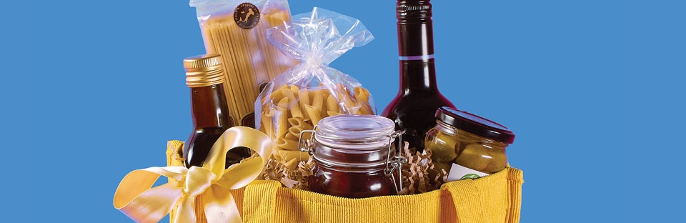 Arrangement of specialty olive oils, premium pasta, olives and a favorite wine in a reusable tote